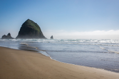 Haystack Rock on a sunny day, with visitors on Cannon Beach, Pacific Northwest, Oregon